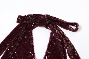 Gros plan détaillé des paillettes bordeaux sur les bretelles d'une robe dos nu