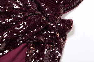 Gros plan du tissu pailleté bordeaux avec des plis torsadés et une texture scintillante