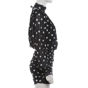 Close-up of black and white polka dot mini dress with elegant ruched details on the skirt
