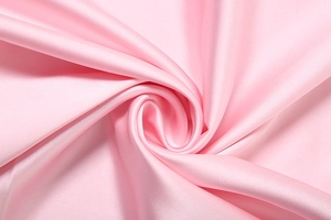 Close-up of pink satin fabric showing luxurious silky luster and smooth texture details