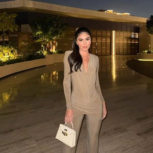 Detail of slim fit khaki jumpsuit with deep V-neck cross drape and wide leg silhouette