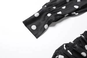 Detail of sheer black polka dot mesh fabric with shirred texture and cuffed sleeve hem