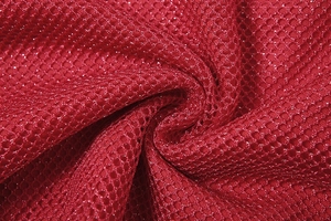 Nahaufnahme von rotem Wabennetzgewebe mit schimmernden Glitzerdetails und Faltenwurf