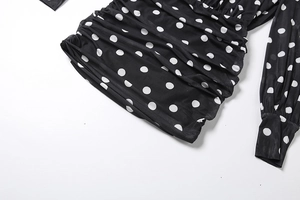 Detail of ruched polka dot mesh fabric with tight cuffs on a black mini dress