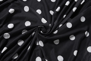 Detailed view of black polka dot fabric with soft drapes and elegant swirl texture