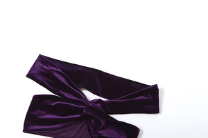 Detail eines dunkelvioletten Samtstirnbands mit stilvollem Knotendesign vorne