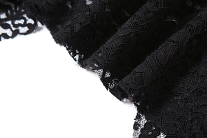 Detailed close-up of black lace fabric with hollow floral patterns and fringe design