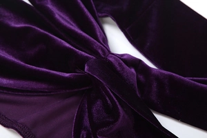 Detail aus dunkelviolettem Samtstoff mit hochwertigem Knotendesign und feinen Nähten
