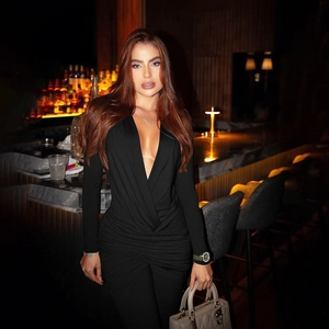 Detail of the deep V-neckline and cross-pleated waist on a slim black long-sleeve jumpsuit
