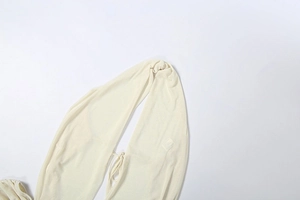 Detail of beige sheer knit fabric with halter neck strap and soft ribbed texture