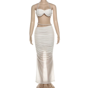 Detail eines weißen gerafften Zweiteilers mit Perlenketten am Oberteil und Maxirock