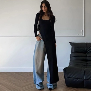Detail of a black long sleeve high slit tunic styled with wide leg light blue denim jeans