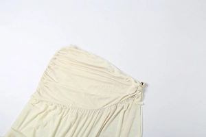 Detailed close-up of beige ruched fabric with golden beads and elegant pleats