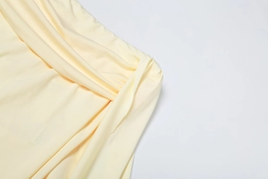 Detail of elegant cream yellow fabric featuring sophisticated pleated knot and soft textures