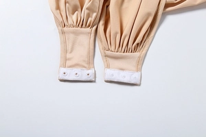 Detail shot of apricot bodysuit crotch area with three reinforced white snap buttons