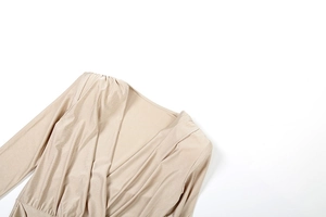 Detail of champagne deep V-neck long sleeve jumpsuit with elegant pleats and silky fabric