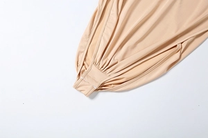 Detail of high-stretch beige bodysuit featuring snap closure and pleated fabric texture