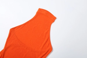 Detail view of bright orange halter knit top featuring fine texture and seamless stitching