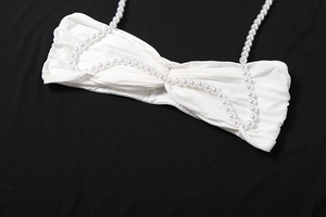 Detail des weißen Bandeau-Tops mit Knotendesign und Trägern aus weißen Perlen