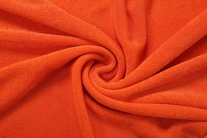 Detailed macro shot of high-density bright orange ribbed knit fabric with soft texture