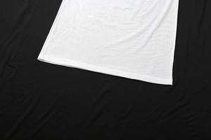 Detail des weißen Strick-Tops mit präziser Doppelnaht am Saum auf schwarzem Stoff