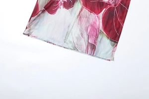 Détail de l'ourlet de la robe avec imprimé floral rouge et fente latérale discrète