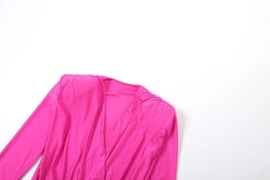 Detail of magenta long sleeve jumpsuit featuring a deep V-neck and pleated shoulders