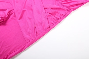Detailed view of fuchsia long sleeve jumpsuit with crossover ruched waist design