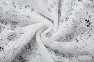 Gros plan sur le tissu en dentelle florale blanche avec broderies et détails ajourés