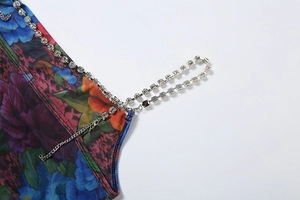 Detail of rhinestone chain straps on a floral print mesh dress with purple and orange patterns