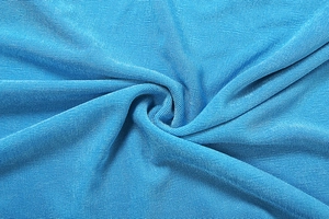 Close-up detail of blue textured fabric with elegant fringe design and soft drape