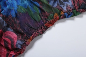 Macro detail of floral mesh fabric showing elastic ruched cuff and vibrant red blue print