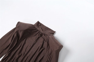 Detalle del vestido marrón ajustado con cuello alto fruncido y hombreras acolchadas