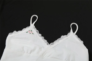 Gros plan détaillé du caraco blanc avec bordure en dentelle et broderie florale rose