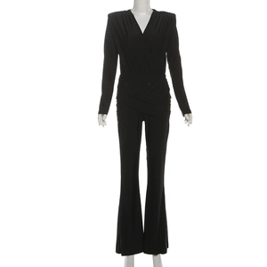 Detail of black long sleeve jumpsuit featuring deep V-neck and pleated waist crossover
