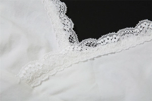 Détail rapproché de la bordure en dentelle blanche et de l'encolure en V du haut