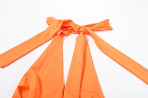 Detail of orange halter neck tie closure with smooth elastic fabric on white background