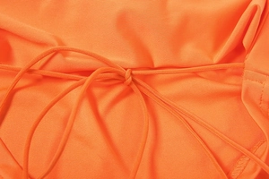 Detail of a bright orange drawstring knot and fabric texture on a slim-fit outfit