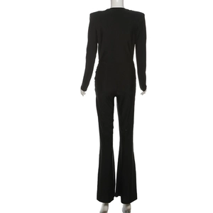 Back view of slim fit black long sleeve jumpsuit with shoulder pads and flared legs