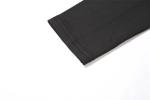 Detailed close-up of double-stitched hem on a black long-sleeved elastic jersey top