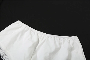 Détail d'un short en coton blanc avec taille élastique et bordure en dentelle florale