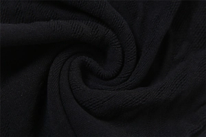 Gros plan sur un tissu en maille noire avec texture spirale et détails côtelés