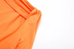 Detail of bright orange fabric with ruched texture and silky pleated draping design