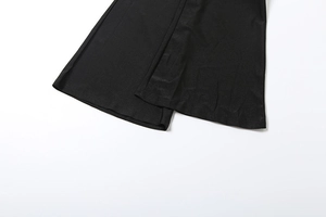 Detailed close-up of the uniform stitching and hem on black flared jumpsuit leg trousers