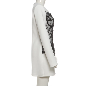 Détail de la dentelle noire contrastée sur la robe courte blanche moulante à col V