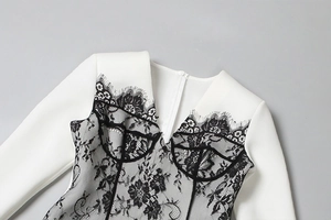 Détail du décolleté en V profond avec dentelle noire contrastée sur la robe blanche