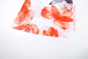 Macro detail of vibrant orange floral print on high-quality white chiffon fabric texture