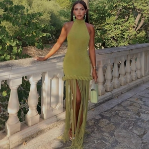 Avocado green halter dress with braided waist and long tassels in a garden setting