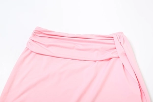 Detail of light pink high-waist ruched skirt featuring elegant side drape and folding