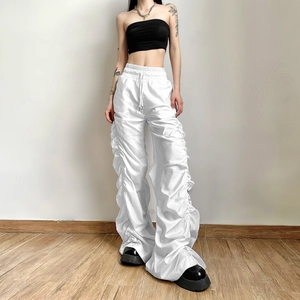 Detail view of white high-waist wide-leg trousers featuring lateral stacked ruching accents